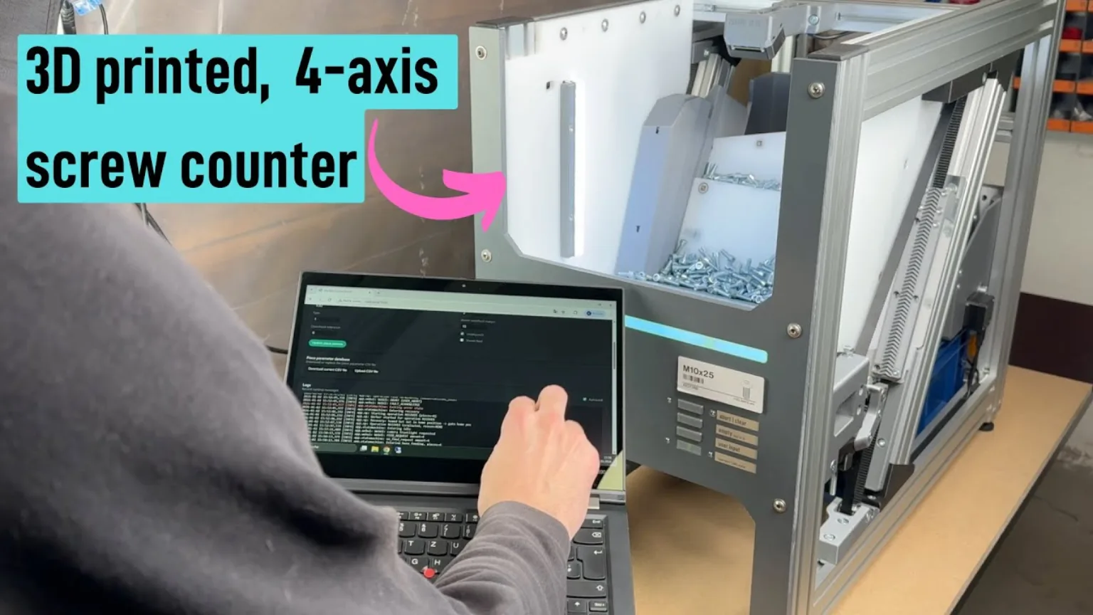 A person operating a laptop beside a four-axis screw-counting machine filled with fasteners.