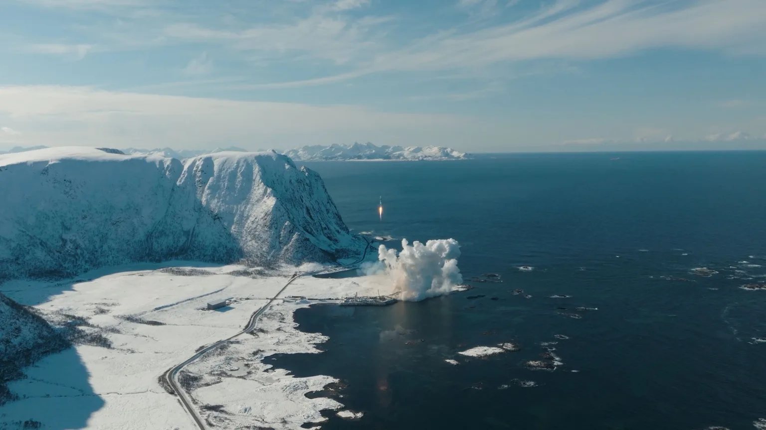 Spectrum rocket lifting off from the snow-covered Andøya Spaceport over the sea, seen from a drone.