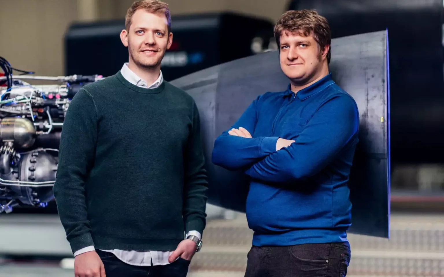 Co-founders Daniel Metzler and Josef Fleischmann standing in front of a rocket engine and a Spectrum stage.