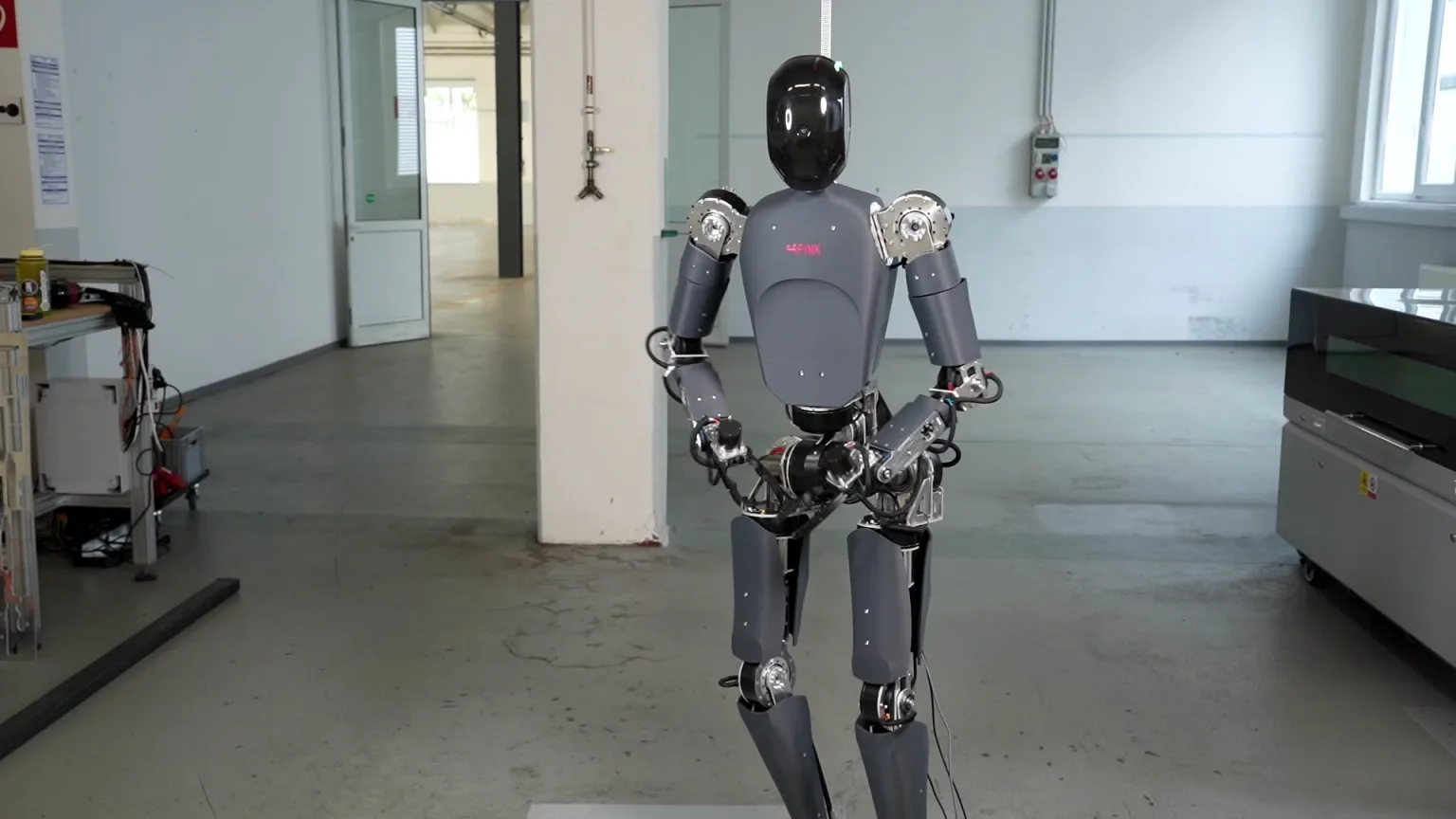 The grey P0 humanoid robot standing in Pink Robotics' Darmstadt workshop.