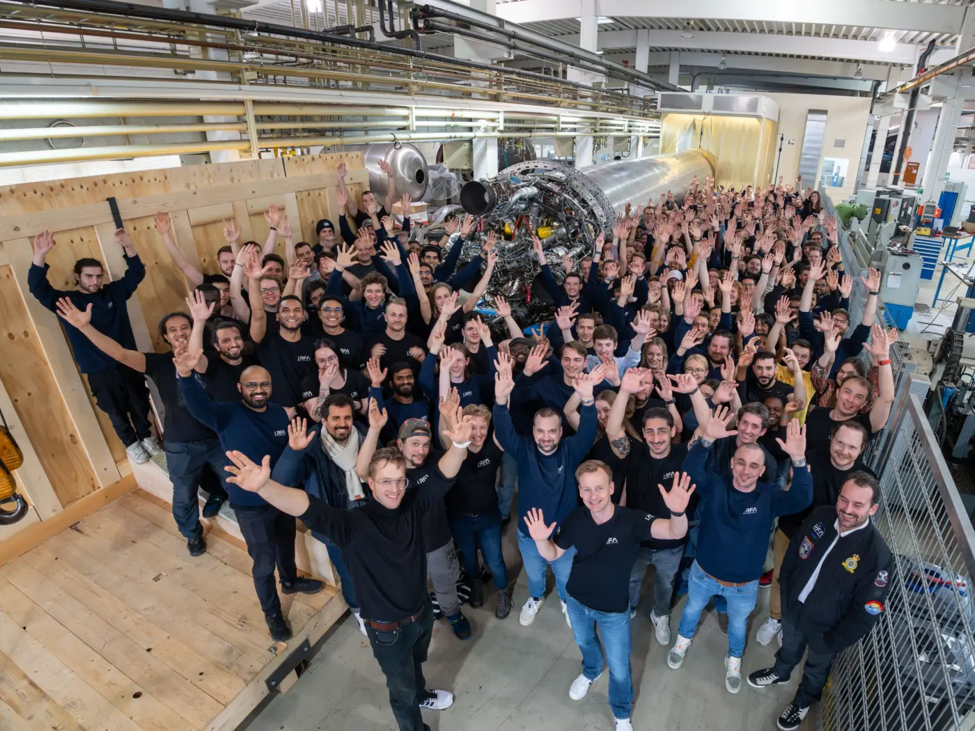 The RFA team waving in front of an RFA One first stage on the factory floor in Augsburg.