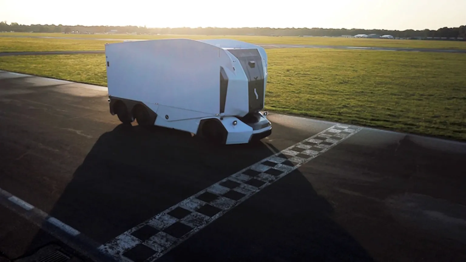An Einride autonomous electric truck crossing a checkered finish line on a test track.